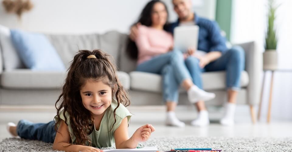 A girl draws next to her parents